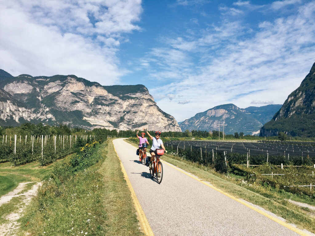 Cyclist on the Adige Cycle Path with mountain views between Bolzano and Trento, Italy.