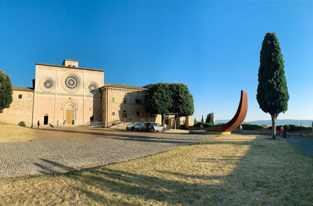 Historic church with cypress trees under a blue sky.