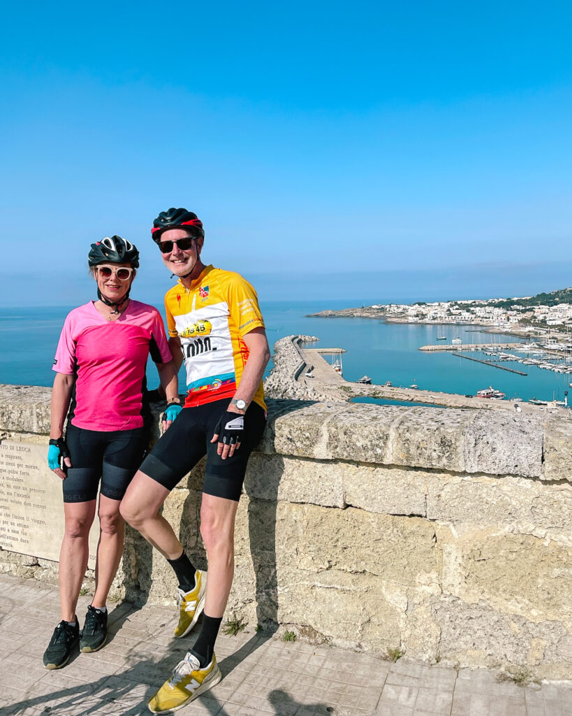 Two cyclists with a coastal panorama in the background, Puglia, Italy.